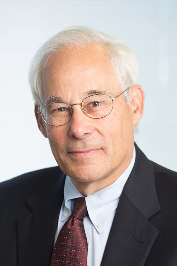 A headshot image of Don Berwick wearing a black suit and red tie.