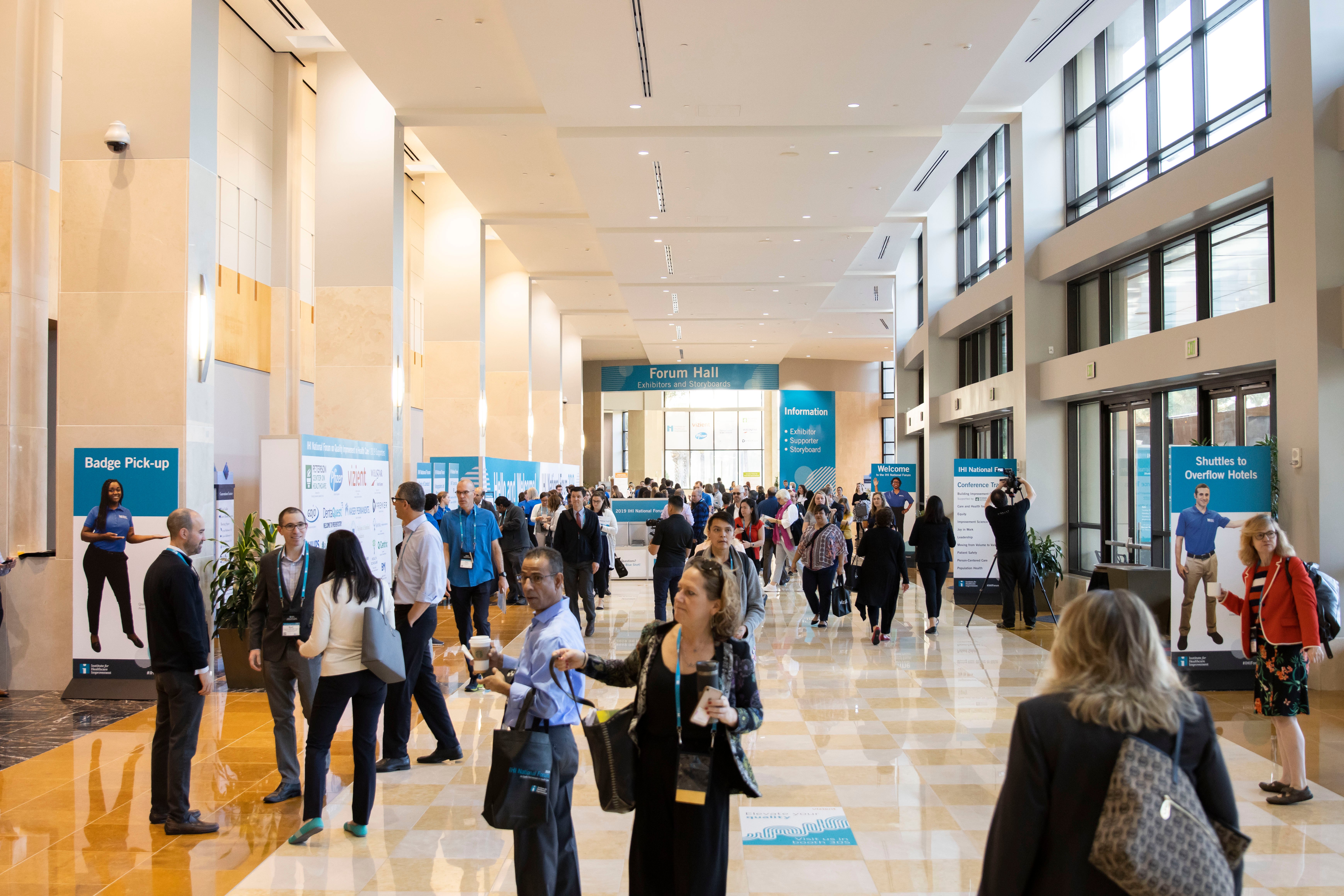 A busy conference hall full of attendees walking.