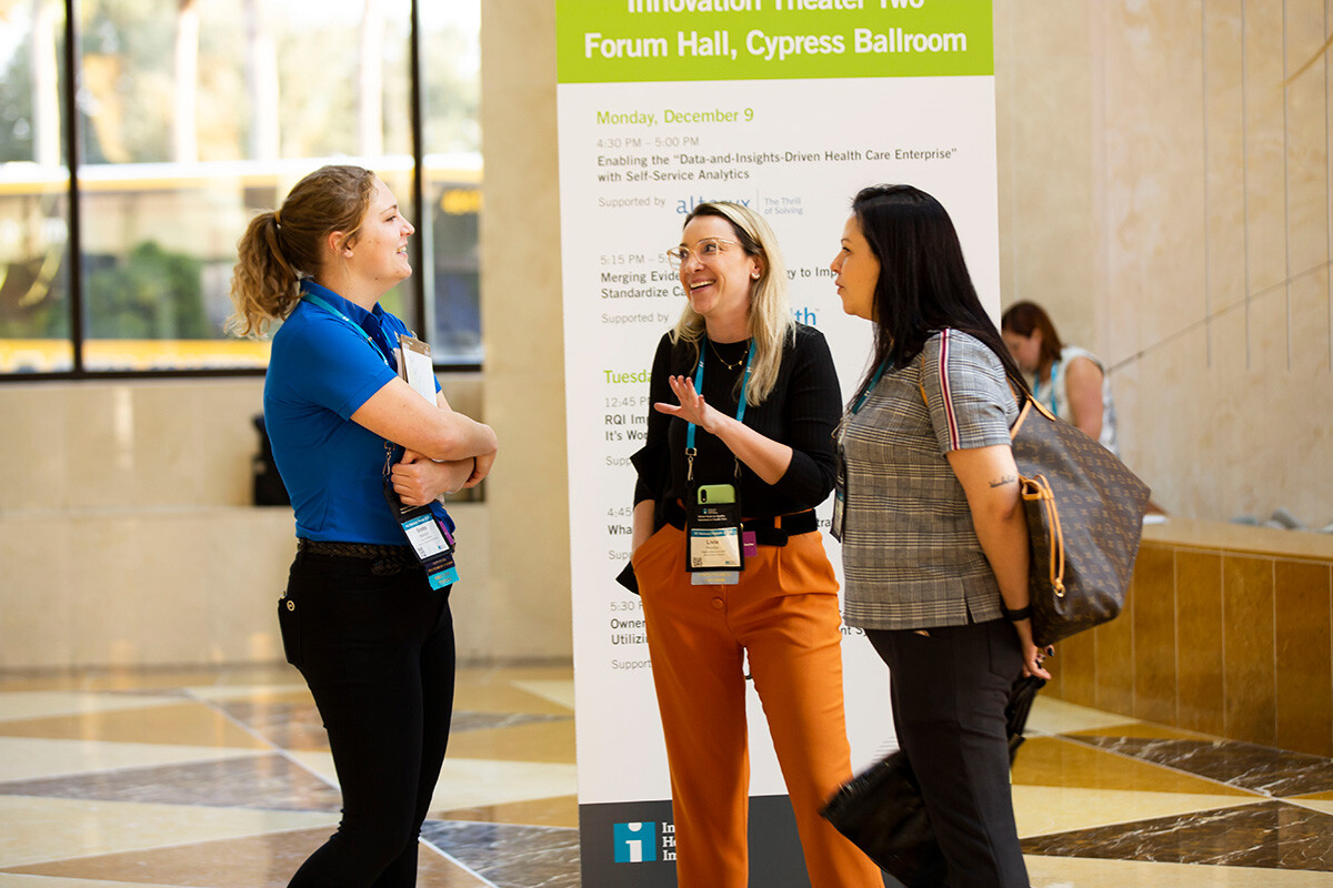 2 conference attendees speaking with a conference staff member.