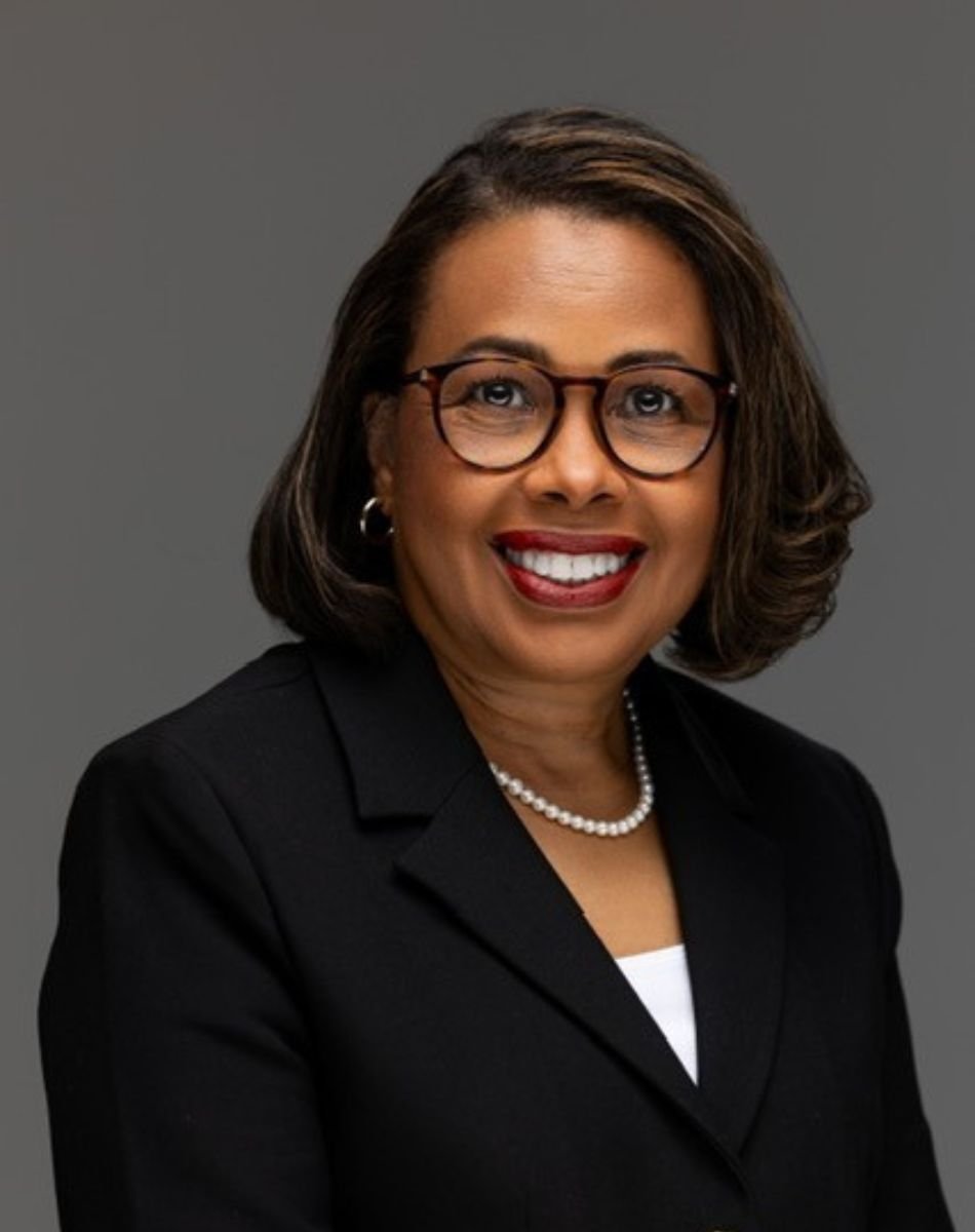 A headshot image of Sylvia Trent-Adams, wearing a black blazer against a grey background.