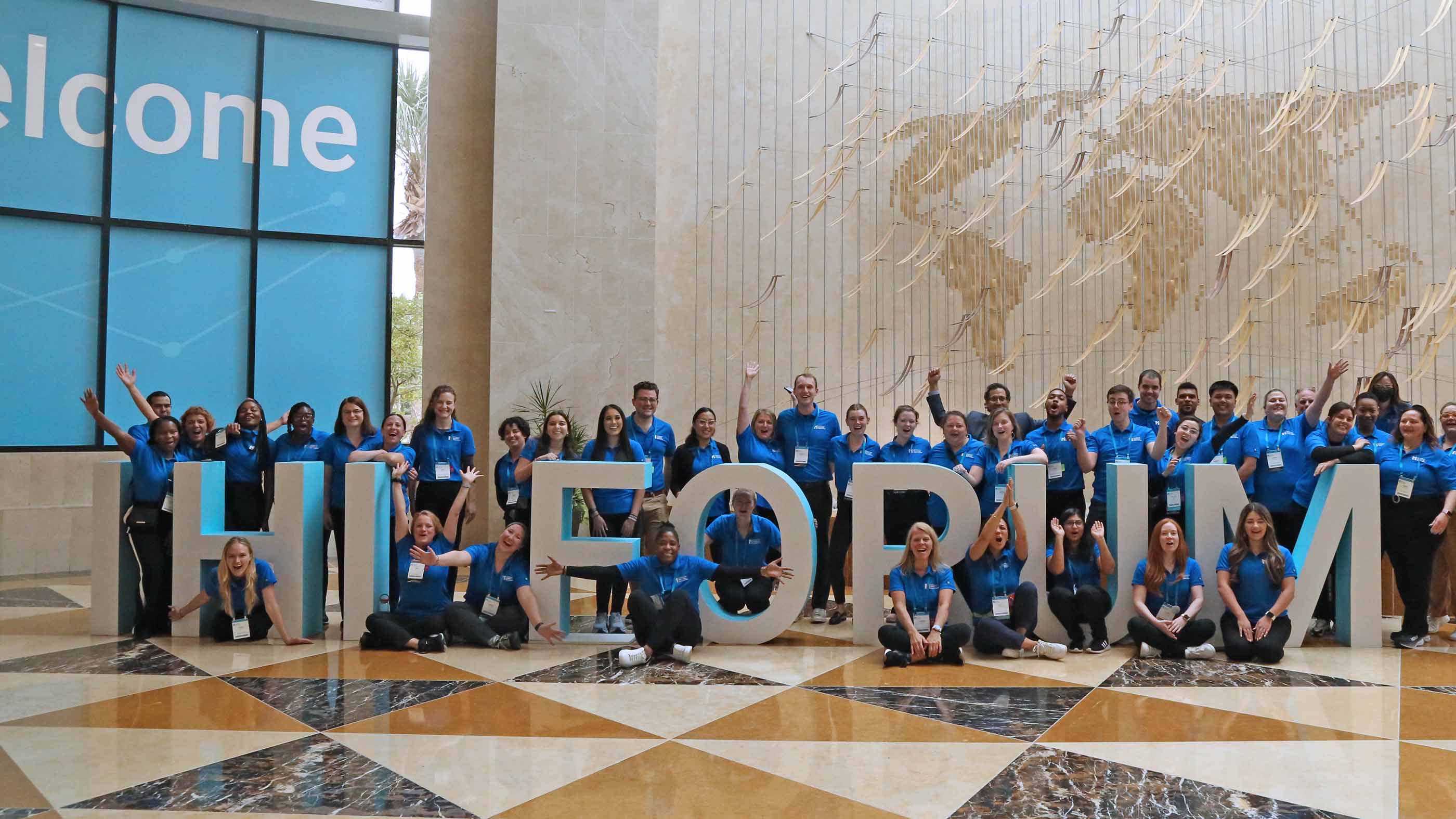 A group picture of IHI Staff members in blue shirts posing with large letters that spell 
