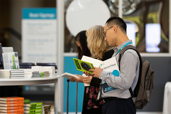 A male conference attendee at the Forum Bookstore reading a book.